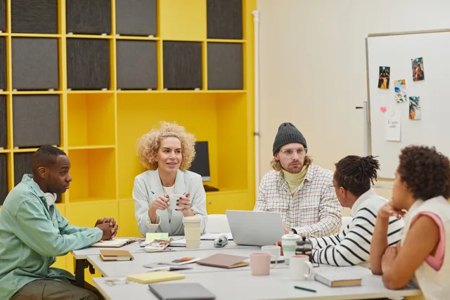 A diverse group of coworkers engaging in a meeting around a table in a modern office setting. Arbetsmarknadens struktur: så läser ni statistik, brist och förändring